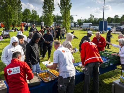 Red Cross staff hand out evening meal outside an overcrowded asylum seekers' registration