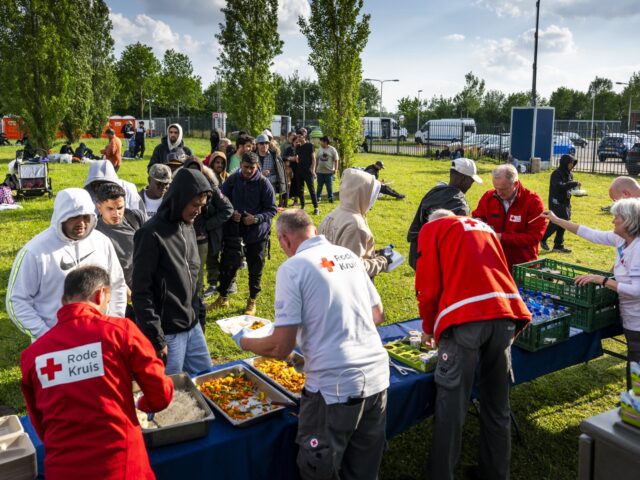 Red Cross staff hand out evening meal outside an overcrowded asylum seekers' registration