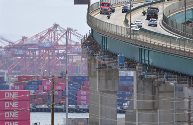LOS ANGELES, CALIFORNIA - MAY 28: Vehicles pass near shipping containers stacked at the P