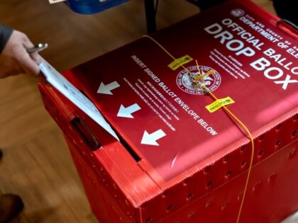 A voter places their ballot in an official ballot drop box at a polling location during a