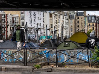 Migrants gather at a temporary migrant camp under an elevated section of Metro line 2, in