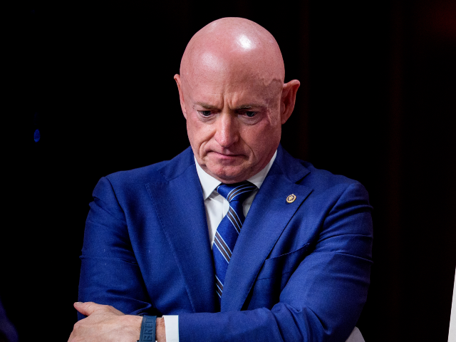 WASHINGTON, DC - JUNE 17: Sen. Mark Kelly (D-AZ) stands next to a poster that reads "Trump