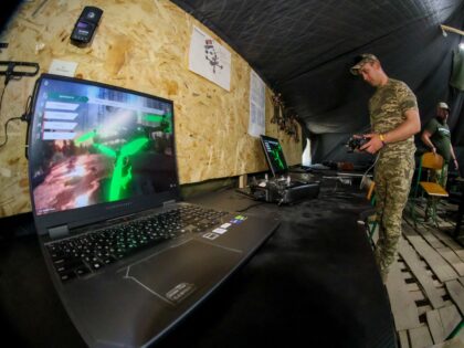 A serviceman stands next to a laptop at the Rarog training center of the 427th Separate Un