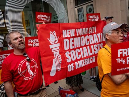 Demonstrators hold a "Democratic Socialists of America" banner ahead of a vote by the Rent