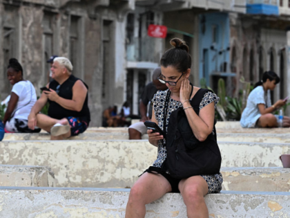 People use their mobile phones during a power outage in Havana on July 7, 2026. Cubans wer