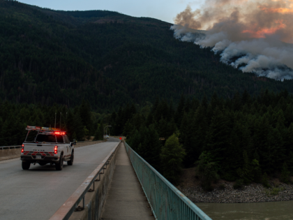 An emergency vehicle crosses the Fraser River towards the Brunswick Creek Wildfire near Bo