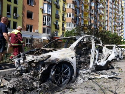 People walk past damaged cars parked in a street following missile strikes in Kyiv on July