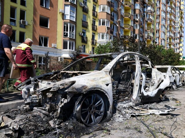People walk past damaged cars parked in a street following missile strikes in Kyiv on July