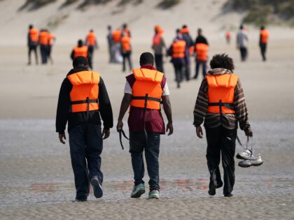 People thought to be migrants leave the beach after failing to board a small boat off the
