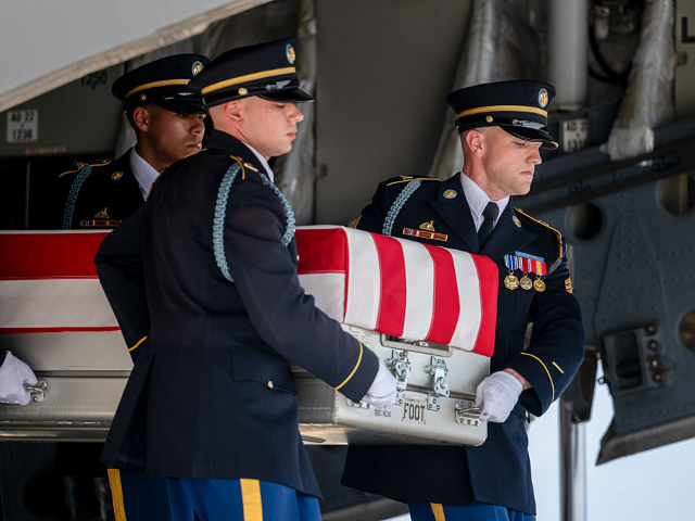 Members of a US Army carry team transports a flag-draped transfer case containing the rema