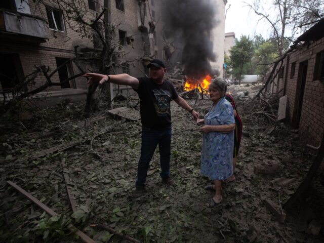 SLOVIANSK, UKRAINE - JULY 24: A man shows two residents the way out of a destroyed buildin