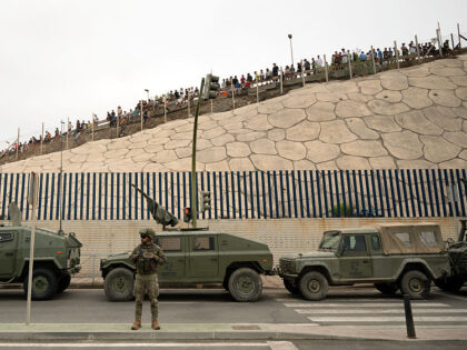 TOPSHOT - Spanish military personal patrol as migrants try to cross the border barrier wit