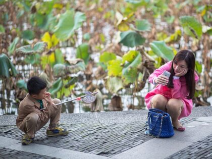WEST LAKE, HANGZHOU, CHINA - 2014/11/01: A young mom is taking selfies beside a lotus pond