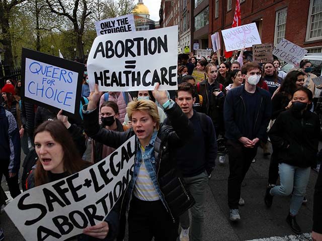 Protesters hold signs reading abortion equals healthcare, queers for choice, and safe and