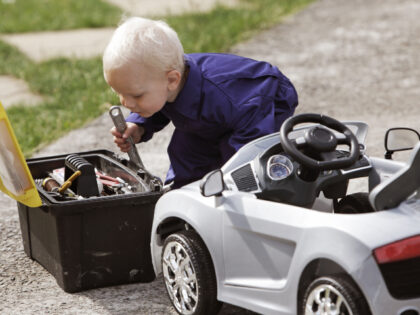Little boy fixing toy car with adult tools