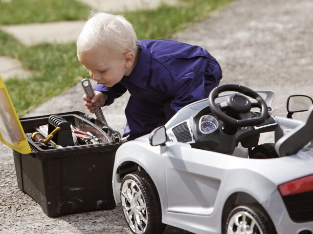 Little boy fixing toy car with adult tools