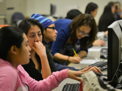 Volunteer Daniela Martinez, 2nd from L, closely reads the college essay of high school stu