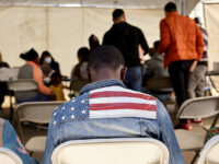 SOMERTON, ARIZONA - MAY 12: An immigrant from Ghana wears an American flag jacket at a migrant transition center for asylum seekers released from Border Patrol custody, after crossing into the United States, on May 12, 2023 in Somerton, Arizona. The U.S. government's Covid-era Title 42 policy, which for the past three years had allowed for the quick expulsion of irregular migrants entering the country, expired last night. About 25,000 immigrants were in the custody of U.S. Customs and Border Protection yesterday at the sunset of the policy. (Photo by Mario Tama/Getty Images)