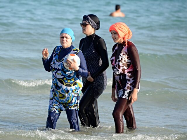 Fully covered Tunisian Muslim women walk in the water on August 16, 2016 at Ghar El Melh b