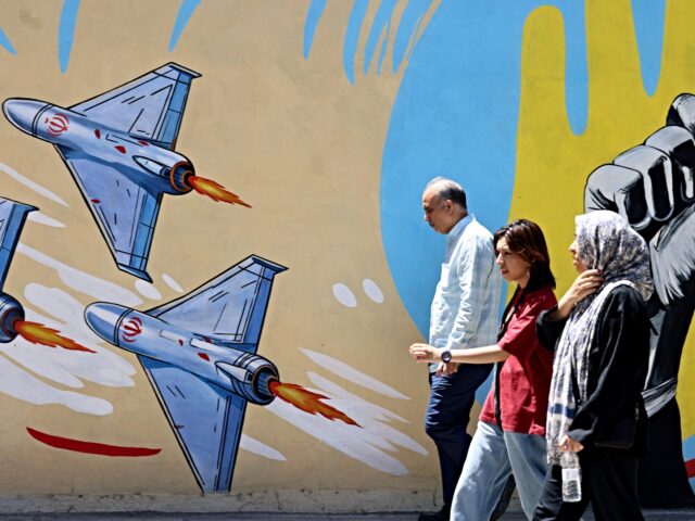 Iranians walk past an anti-US and anti-Israel mural painted on a wall in the capital Tehra