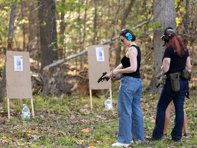 A student (L) reloads her pistol during an introductory firearms class at a backyard shoot