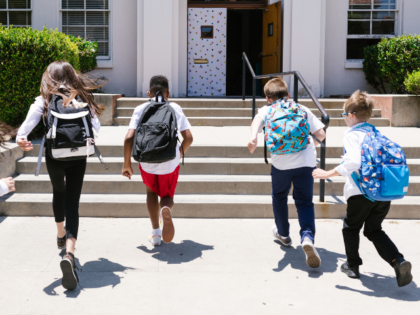 students with backpacks running at school