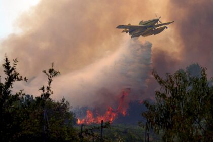 A plane dumps water over a wildfire burning west of Madrid on July 26, 2026