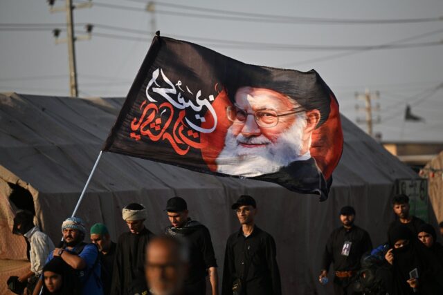 Shiite Muslim pilgrims hold a flag bearing the portrait of Iran's slain supreme leade