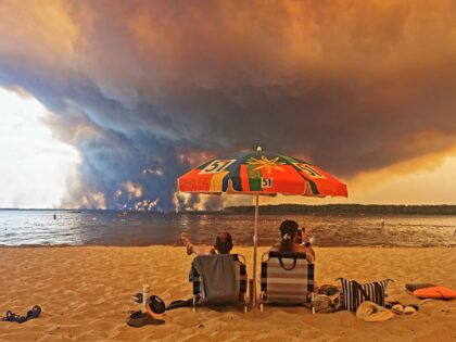 Beach goers sit on the beach of Moutchic in Lacanau, southwestern France on July 24, 2026,