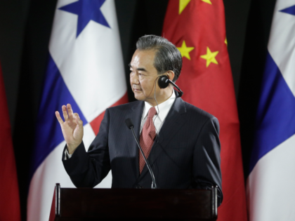 Chinese Foreign Minister Wang Yi, gestures after adjusting his translator device during a
