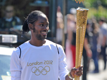 Torchbearer Jason Arday carries the Olympic Flame on the Torch Relay leg between Sutton an