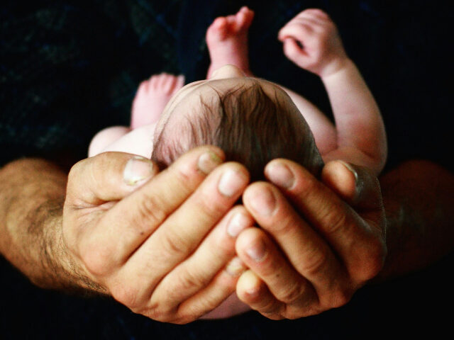 Baby cradled in man's hands