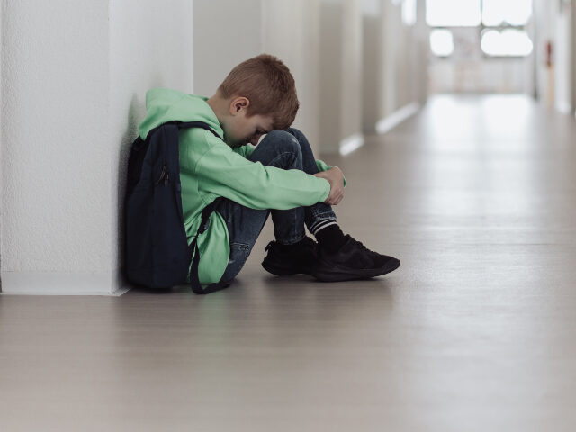 Boy sitting with head down in corridor
