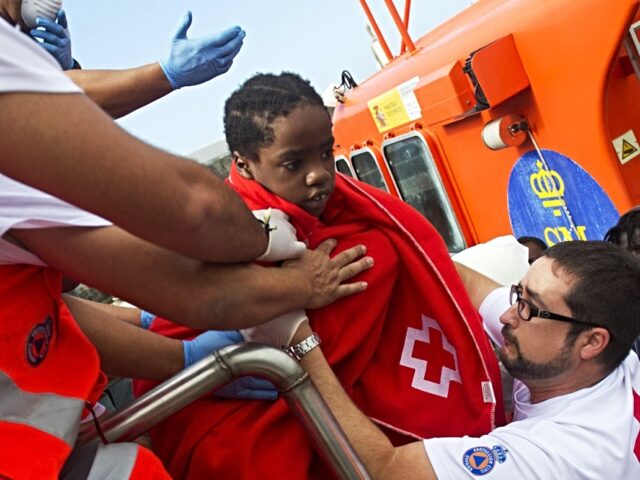 Members of the Spanish emergency services and Red Cross help a young girl to disembark a c