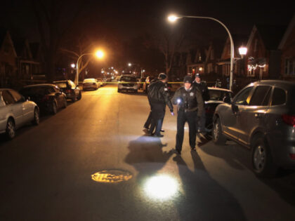 Police investigate the scene of a shooting where a 23-year-old woman was shot in the chest