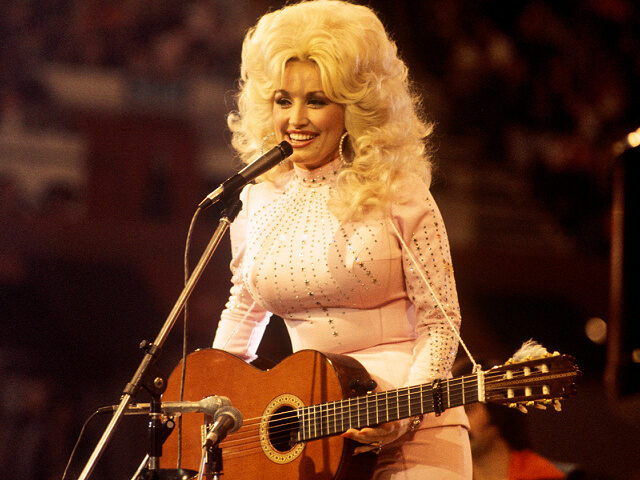 Dolly-Parton-performs-with-guitar-1976-file-getty UNITED KINGDOM: American singer, songwriter and actress Dolly Parton, performs with a guit