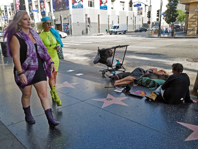 GettyImages-1594188848 Los Angeles, CA - August 12: People who are displaced sit on the sidewalk with two dogs on