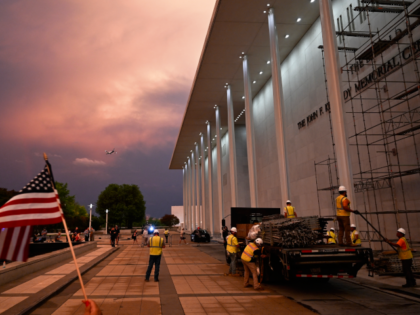 An American flag is waved as workers build scaffolding on the Donald J. Trump and John F.