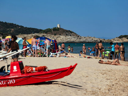 Travel Destination: Sardinia, Italy A red lifeguard rescue boat rests while people are at Su Giudeu beach in south Sardinia, I