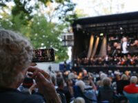 24 July 2026, Bavaria, Bayreuth: A spectator films the open-air festival in the park before the start of the 2026 Richard Wagner Festival using her smartphone. The Richard Wagner Festival will take place from July 25 to August 26, 2026. Photo: Daniel Löb/dpa (Photo by Daniel Löb/picture alliance via Getty Images)