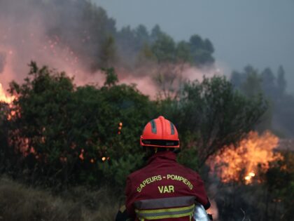 A firefighter look works to put out a wildfire burning through vegetation on the hills of