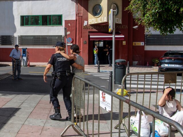 A police officer assists a migrant minor as other migrant minors wait outside the National