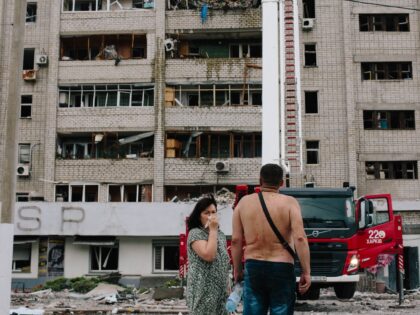 Residents stand near their home, where most of their belongings were destroyed, in an apar