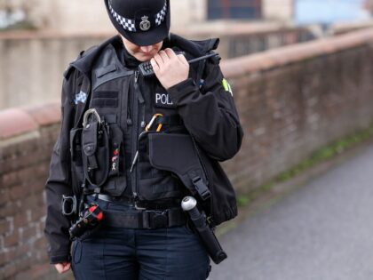 A female police officer with Norfolk Constabulary speaks into her mobile radio whilst on t