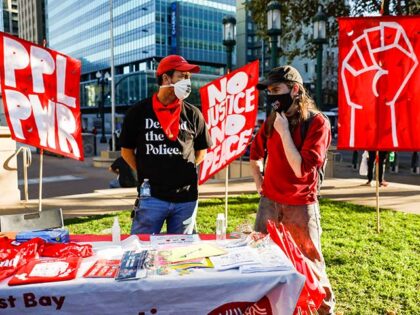 (L-R) AJ Acosta and Will Shattuc chat behind the East Bay Democratic Socialists of America
