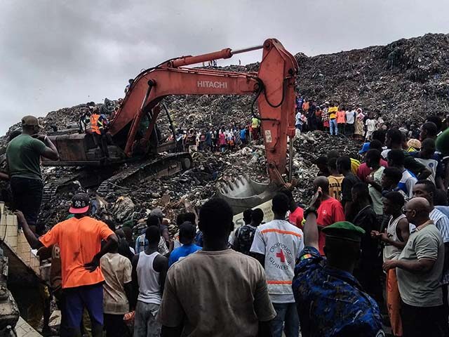 Residents and rescuers use an excavator to search for bodies after a landslide struck the
