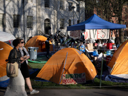Passersby walk past tents at an encampment of students protesting against the war in Gaza,