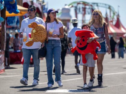 Fairgoers carry their stuffed game winnings as they walk through the fairgrounds at the OC