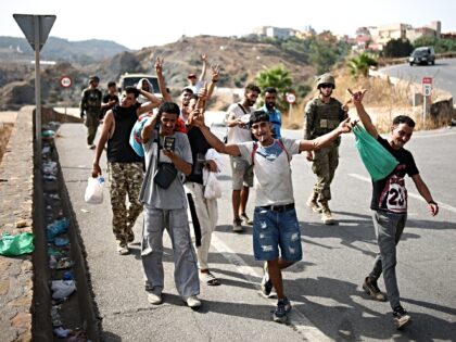 Migrants gesture while being escorted to the Ceuta-Morocco border gate in the Spanish Nort