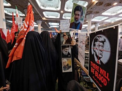 Veiled pro-government supporters walk past portraits of Iran's Supreme Leader Ayatollah Mo